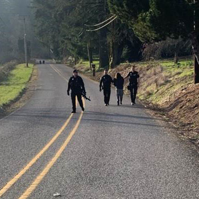 police walking fugitive down a road